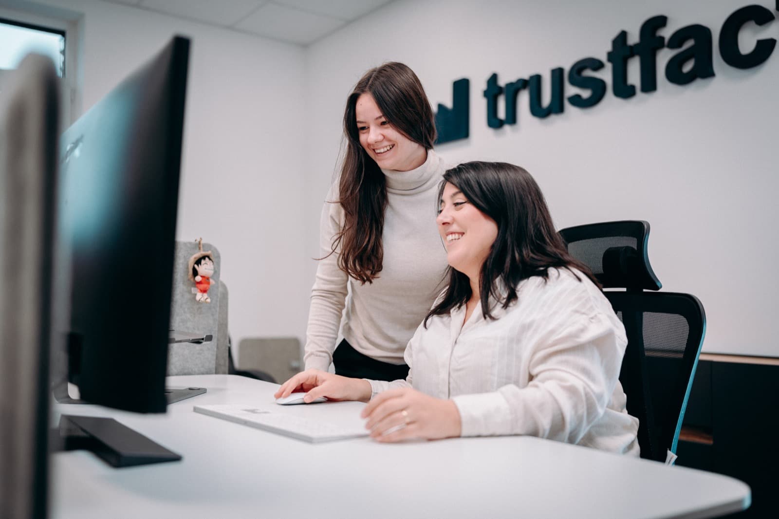 Two Trustfactory team members smiling while reviewing results on screen