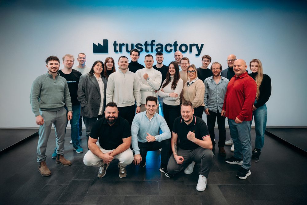 The whole Trustfactory team in front of the logo wall in Mannheim